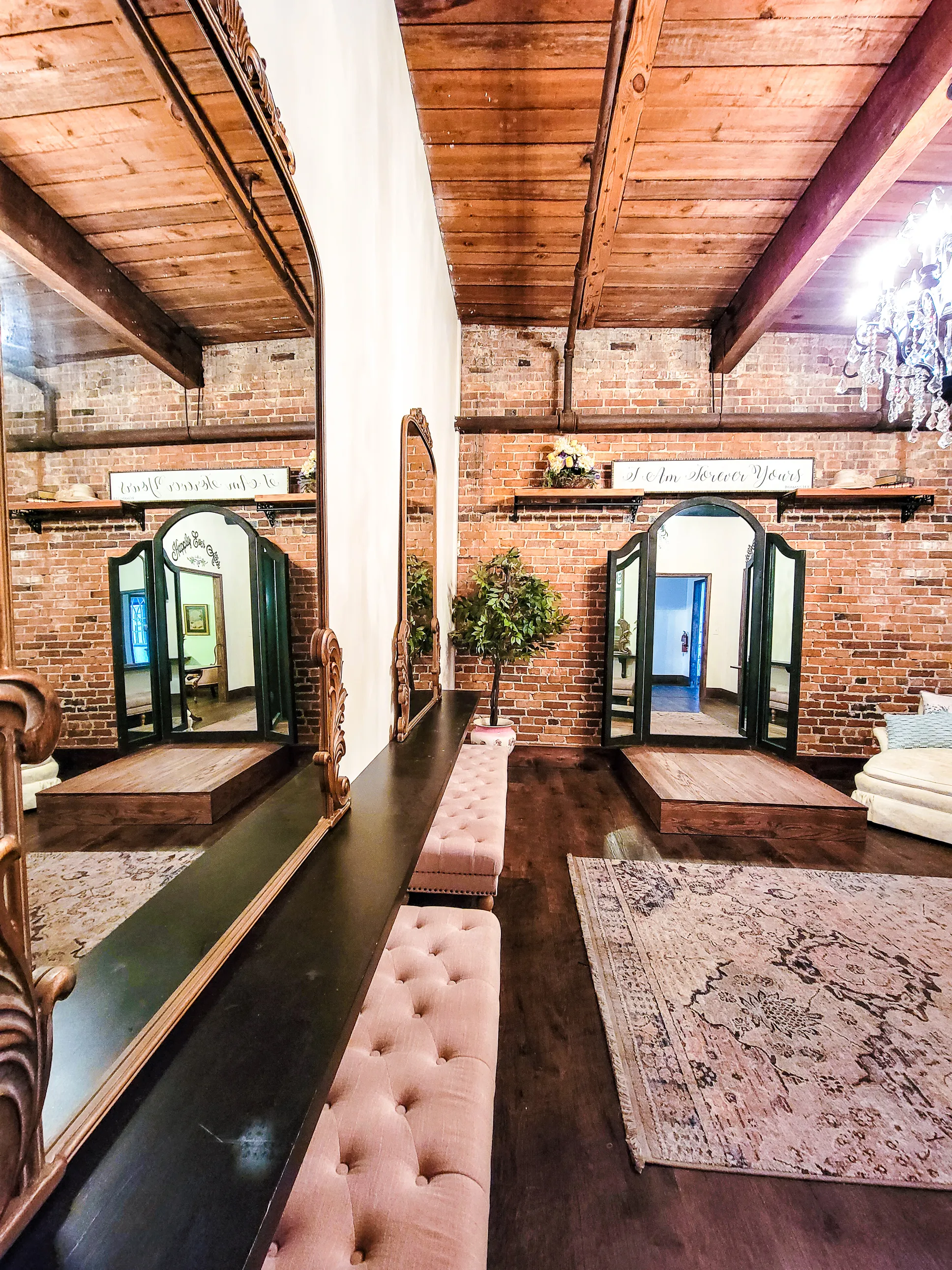 A brick-walled dressing room with full-length mirrors and upholstered benches at The Cotton Loft