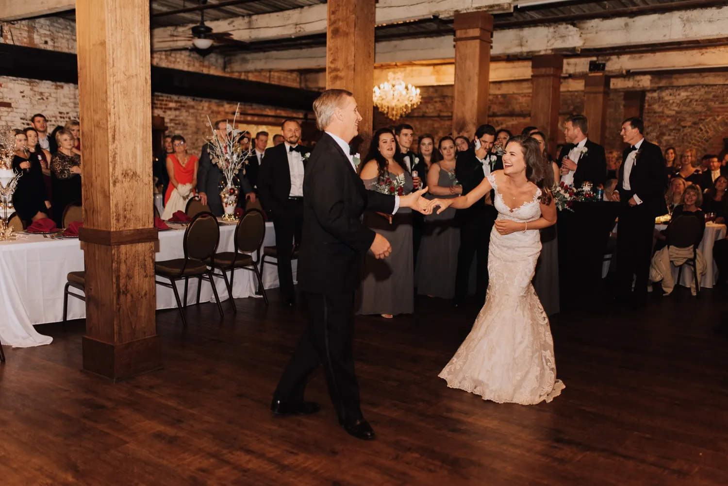 A bride dancing with a guest beneath the chandeliers at The Cotton Loft