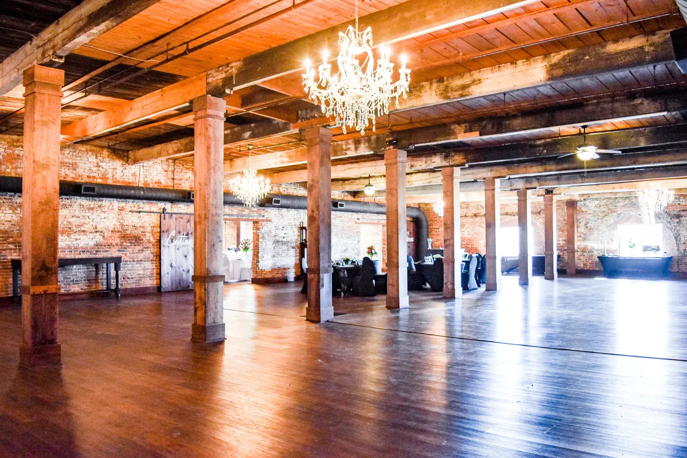 Exposed brick walls, timber columns, wood floors, and chandeliers inside The Cotton Loft