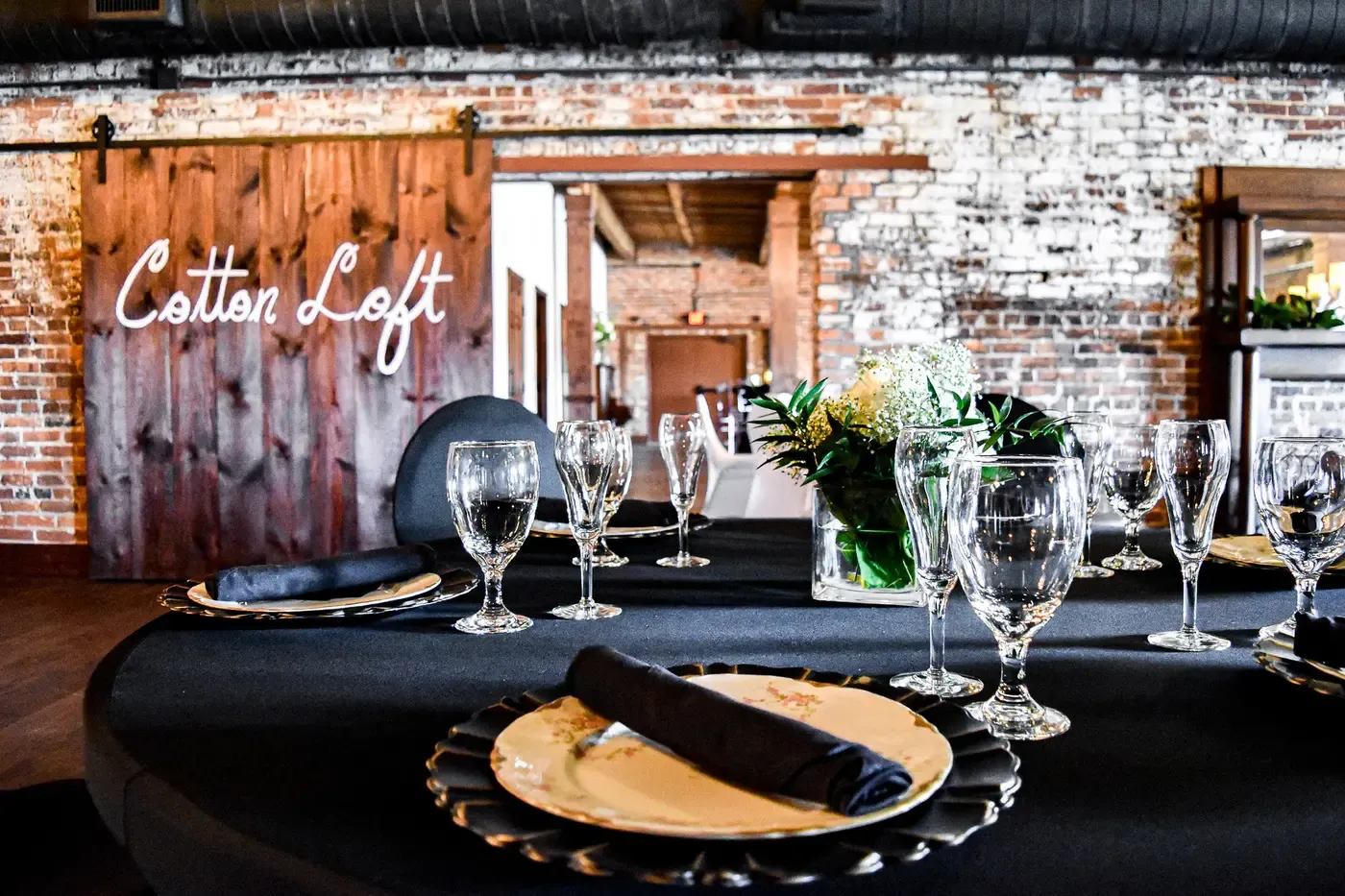 A formal table setting in front of the venue’s wood door and exposed brick wall