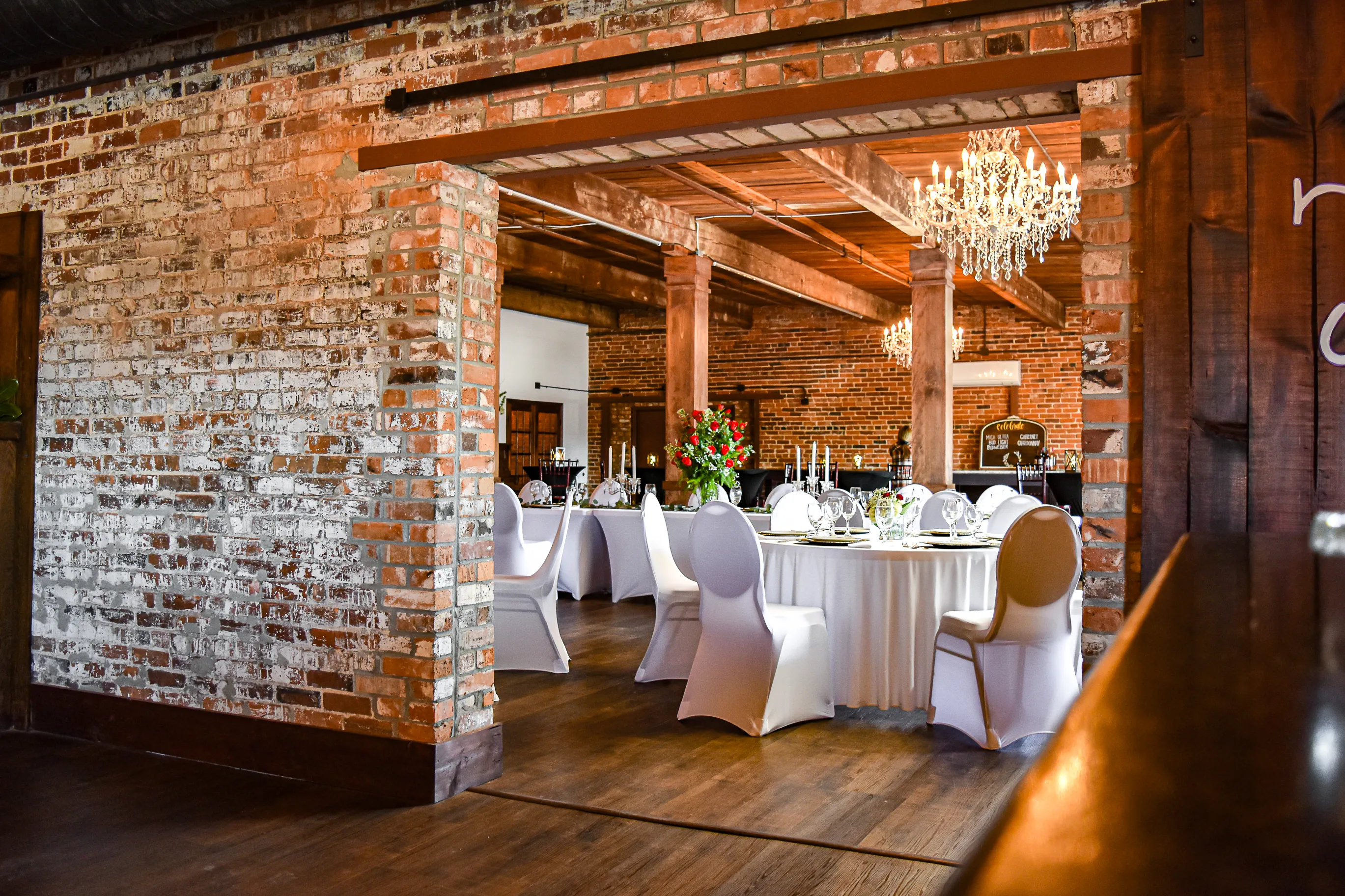 A view through an original brick opening into a reception setting at The Cotton Loft